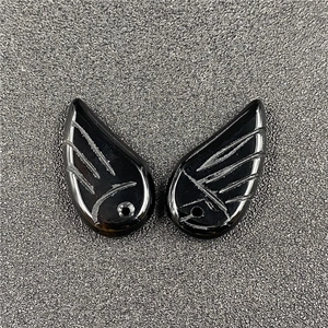 Close-up of polished black wing-shaped pendants with abstract curved engravings for DIY jewelry