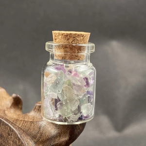 Close-up of mini glass wishing bottle with colorful crystal gravel and cork stopper