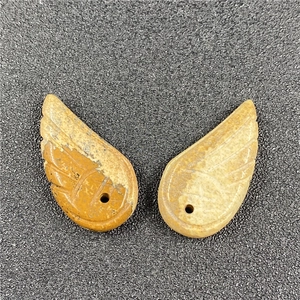 Macro detail of hand-carved natural stone angel wing pendants with fine feather textures