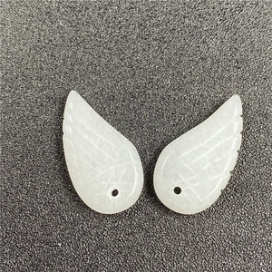 Close-up of white carved angel wing pendants with detailed feather texture and single hole
