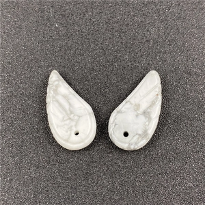 Detailed macro view of white turquoise angel wing pendants with natural marble texture