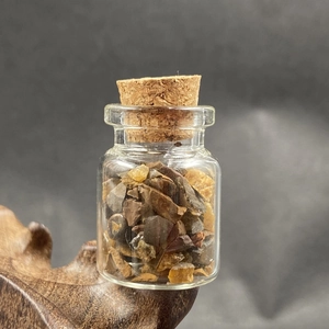 Macro shot of tiger eye crystal chips in a mini glass bottle with cork stopper