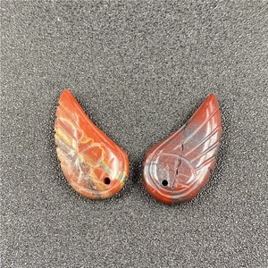 Detailed view of hand-carved red stone angel wing pendants with natural textures