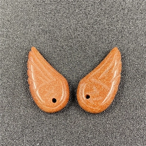 Macro view of engraved angel wing pendants in red-brown sandstone for DIY jewelry making