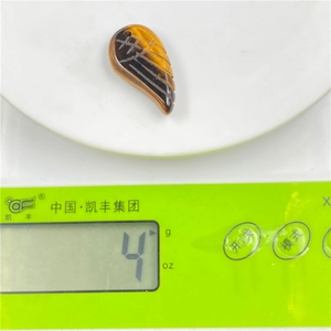 Macro detail of tiger eye angel wing pendant weighing 4g on a precision digital scale