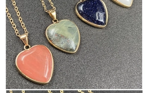 Dettaglio di ciondoli a cuore in pietre multicolori con bordi placcati in oro