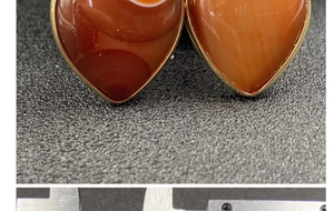 Dettaglio macro del ciondolo a cuore in pietra con bordo dorato misurato con un calibro
