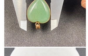 Dettaglio del ciondolo a cuore in pietra verde con bordo dorato misurato con un calibro