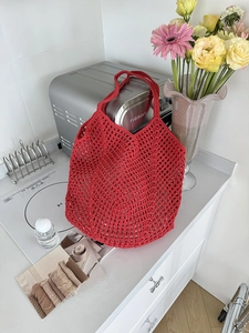 Detailed macro view of red hollow-out crochet mesh pattern on cotton rope shoulder bag