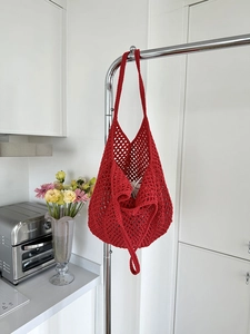 Detail of red crochet mesh tote bag showing intricate hand-knitted hollow pattern design