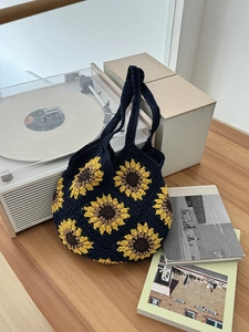 Dettaglio borsa tote blu all'uncinetto con girasoli vicino a un giradischi vintage