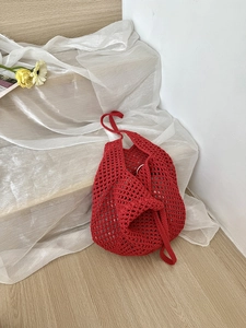 Close-up of red hollow crochet tote bag with intricate handmade mesh texture and cotton cord