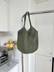 Detail of dark green crochet tote bag showing wide straps and hollow honeycomb weave
