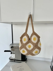 Dettaglio di una borsa tote all'uncinetto marrone con motivi di margherite bianche e gialle