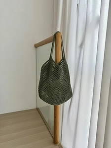 Close-up of army green crochet hobo bag with hollow mesh pattern on wooden railing