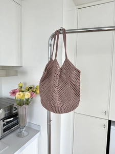 Detail view of pink crochet tote bag hanging in a minimalist kitchen setting