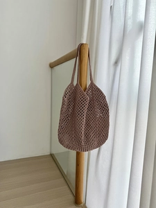 Detailed texture of dusty pink hollow mesh cotton rope tote bag on wooden stairs