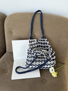 Detail of navy and white hand-woven tote bag with diamond cutout patterns and braided handle
