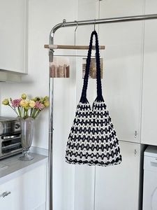Detail of handmade woven tote bag with black and white hollow pattern on a shoulder strap