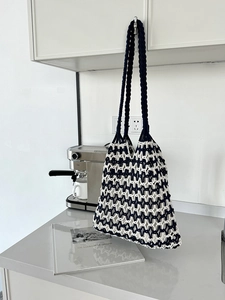 Detail of blue and white crochet knit beach bag with a wide woven shoulder handle