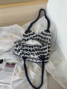 Detail of navy and beige hand-woven shoulder bag showing intricate hollow-out mesh texture