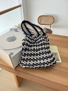 Detail of handmade hollow woven tote bag with blue and beige mesh pattern on wooden table