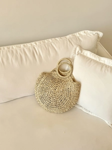 Dettaglio borsa circolare in paglia intrecciata con trama a spirale per spiaggia estiva