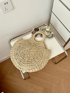 Dettaglio di una borsa rotonda in paglia intrecciata beige con fibre naturali e manici ad anello