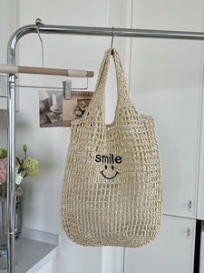 Chic beige hollow straw tote bag featuring black smile embroidery on a woven surface