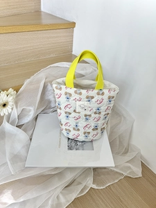 Détail d'un sac cabas en toile matelassée blanc cassé avec anses jaunes et motif chiot
