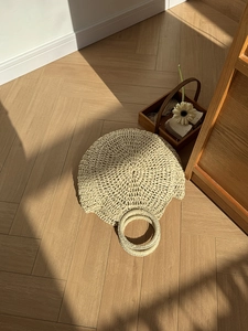 Dettaglio di borsa rotonda in paglia con trama intrecciata su parquet