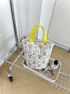 Sac seau matelassé blanc avec anses jaunes et motif caniche mignon sur plateau bois