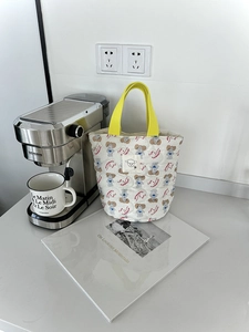 Détail d'un sac seau matelassé avec imprimé ours et poignées jaune vif sur table