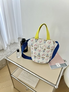 Détail d'un sac seau matelassé avec une sangle bleue et des motifs de chiens mignons