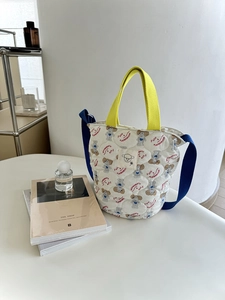 Détail d'un sac seau en coton matelassé avec imprimés de chiens et sangles colorées