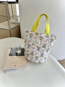 Détail du sac seau matelassé à motif caniche avec anses jaunes et étiquette mouton tissée