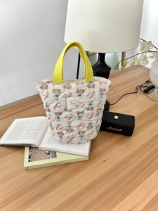 Sac seau matelassé avec imprimé chiot mignon et poignées jaunes sur un bureau en bois