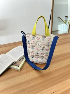 Détail d'un sac fourre-tout matelassé avec motifs de chiens et sangle jaune sur une table