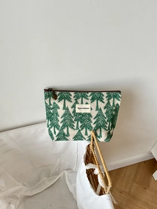 Detail of canvas makeup bag with green pine tree pattern and brown zipper closure