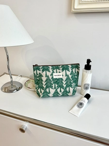 Detail of linen makeup bag featuring green pine tree pattern and zipper closure