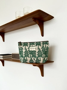 Detail of cotton linen makeup bag with green tree pattern on a wooden shelf