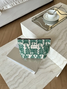 Close-up of cotton linen pouch with green pine tree patterns on a marble surface