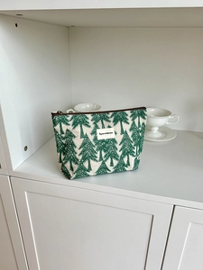 Detail view of cotton linen cosmetic bag with green pine tree pattern and zipper closure