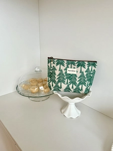 Detail of green pine tree embroidery on cotton linen bag with metal zipper pendant