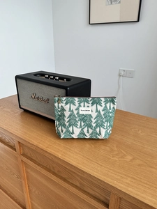 Detailed shot of embroidered linen makeup bag with pine tree pattern and zipper closure