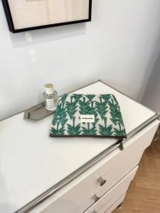Detail of pine tree embroidery on beige linen makeup bag with a vintage metal zipper pull