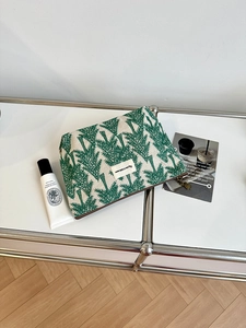 Macro detail of embroidered cotton linen pouch featuring a green leaf pattern and bear charm