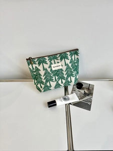 Detail of pine tree print on durable canvas makeup bag with brown zipper closure