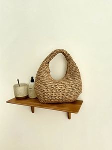 Close-up of hand-woven brown crochet cloud hobo bag on a minimalist wooden shelf