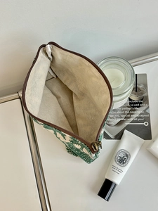 Close-up of printed cotton linen makeup bag with forest pattern and bronze zipper details